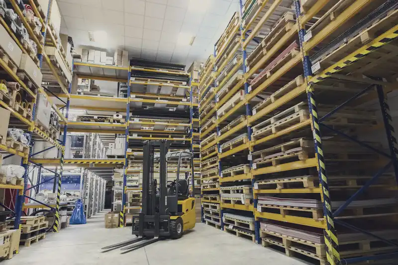 Warehouse with tall pallet racks and a yellow forklift parked between them.